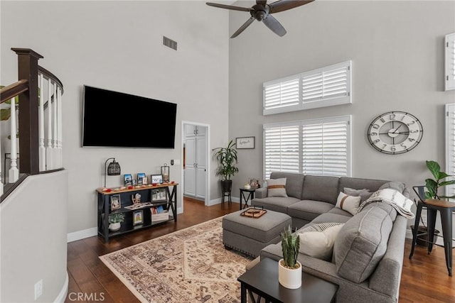 living room featuring a high ceiling, dark hardwood / wood-style floors, and ceiling fan