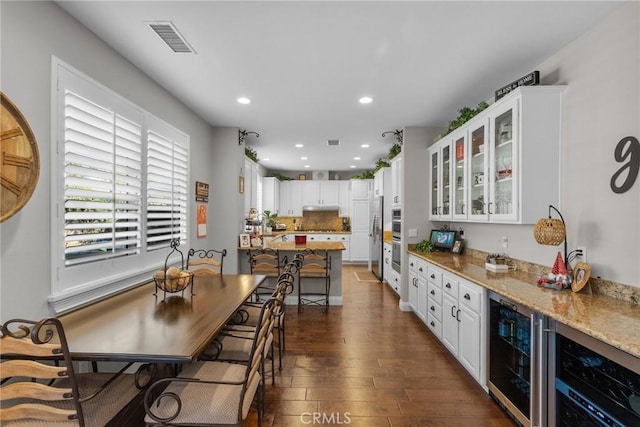 kitchen featuring beverage cooler, light stone countertops, and white cabinets