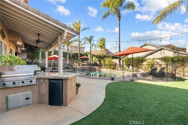 exterior space featuring a bar, an outdoor kitchen, ceiling fan, grilling area, and a fenced in pool