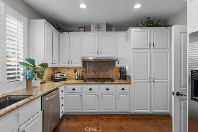 kitchen featuring dark wood-type flooring, backsplash, stainless steel appliances, light stone counters, and white cabinets