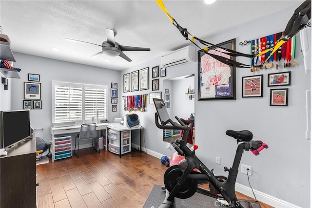 workout area with dark hardwood / wood-style floors, a wall mounted air conditioner, and ceiling fan