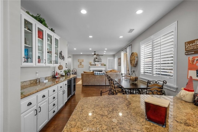 kitchen featuring light stone countertops, dark wood-type flooring, white cabinets, and ceiling fan