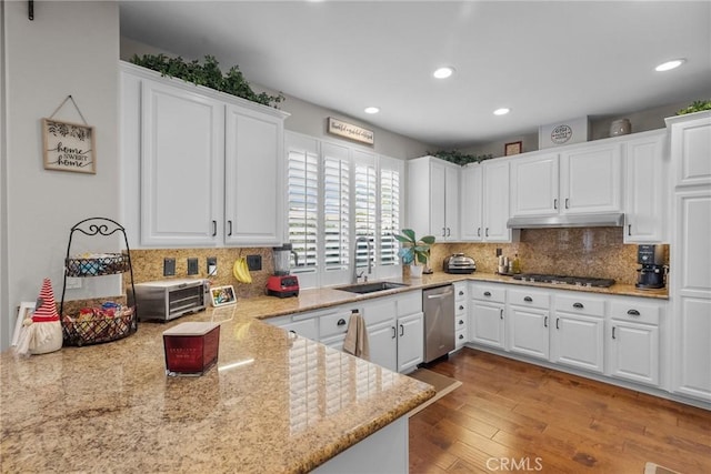 kitchen with appliances with stainless steel finishes, sink, white cabinets, and backsplash