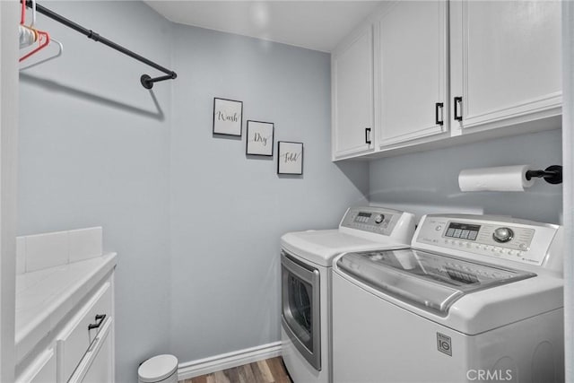 washroom featuring hardwood / wood-style flooring, cabinets, and separate washer and dryer