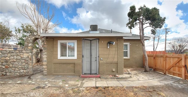 rear view of property with fence and brick siding
