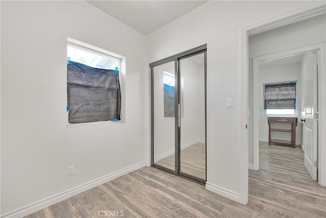 unfurnished bedroom featuring a closet, light wood-style flooring, and baseboards