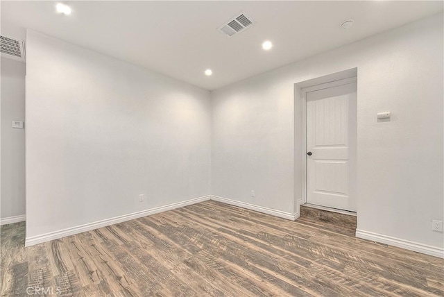 empty room with baseboards, visible vents, and wood finished floors
