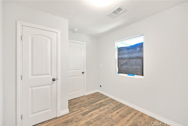 unfurnished bedroom featuring baseboards, visible vents, and wood finished floors