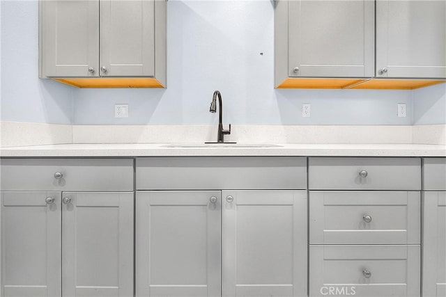kitchen with light countertops, gray cabinets, and a sink