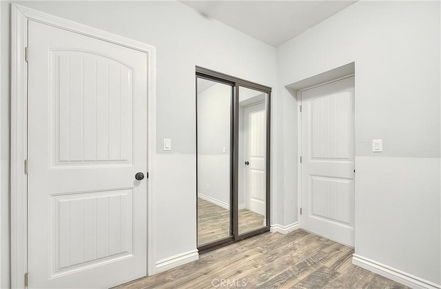 interior space featuring baseboards, a closet, and wood finished floors