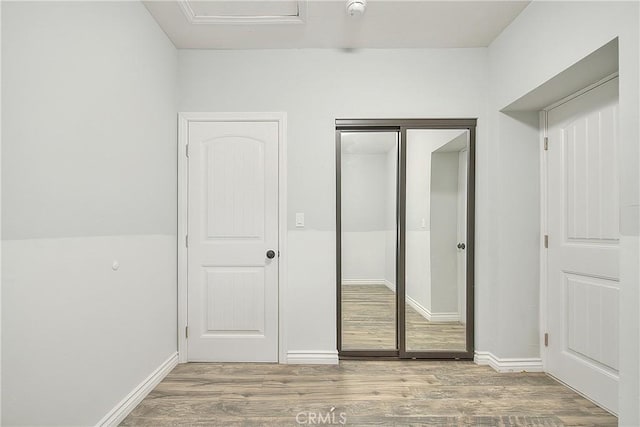 unfurnished bedroom featuring baseboards, a closet, and wood finished floors