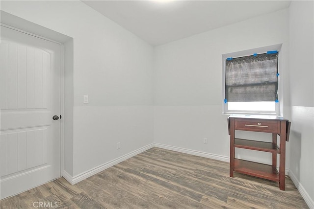 spare room featuring baseboards and wood finished floors