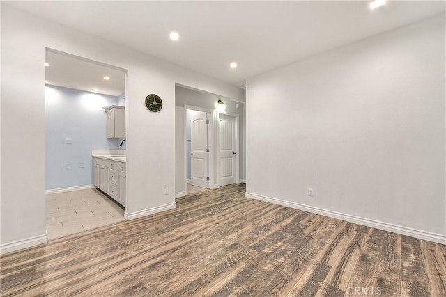 unfurnished bedroom featuring light wood finished floors, ensuite bath, baseboards, and recessed lighting