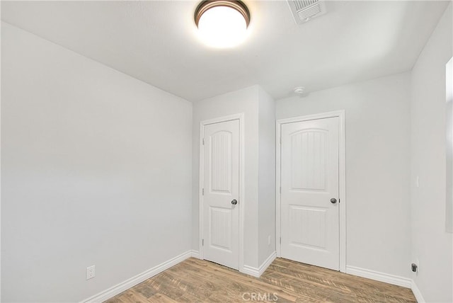 unfurnished bedroom with visible vents, light wood-style flooring, and baseboards