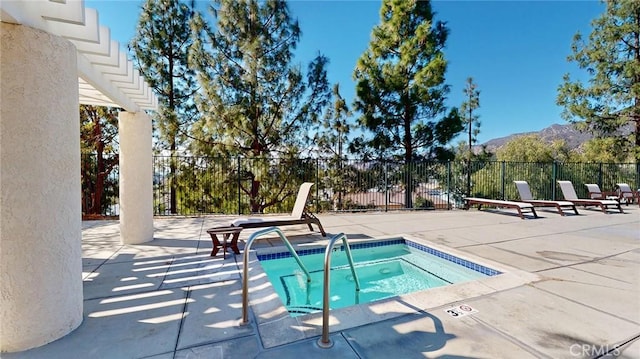 view of pool featuring a hot tub, a mountain view, and a patio