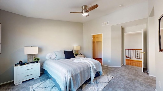 carpeted bedroom with ceiling fan, a walk in closet, and a closet