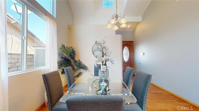 dining area with high vaulted ceiling, hardwood / wood-style floors, and an inviting chandelier