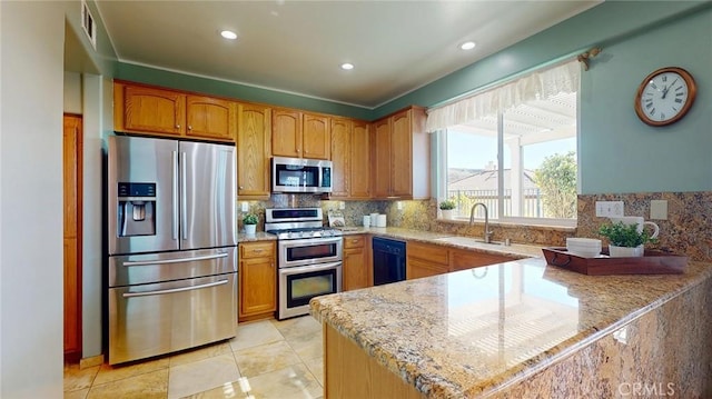 kitchen with light stone counters, sink, backsplash, and appliances with stainless steel finishes