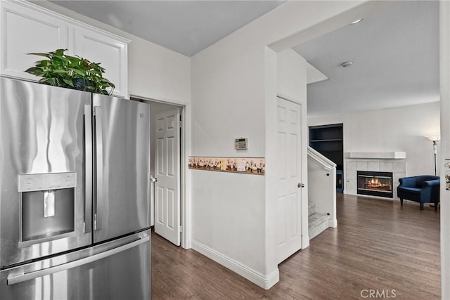 kitchen featuring white cabinets, dark wood finished floors, stainless steel fridge with ice dispenser, open floor plan, and a fireplace