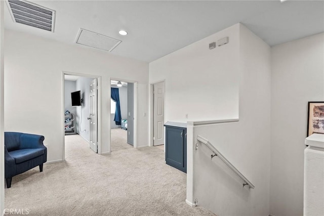 corridor featuring visible vents, light carpet, an upstairs landing, and attic access