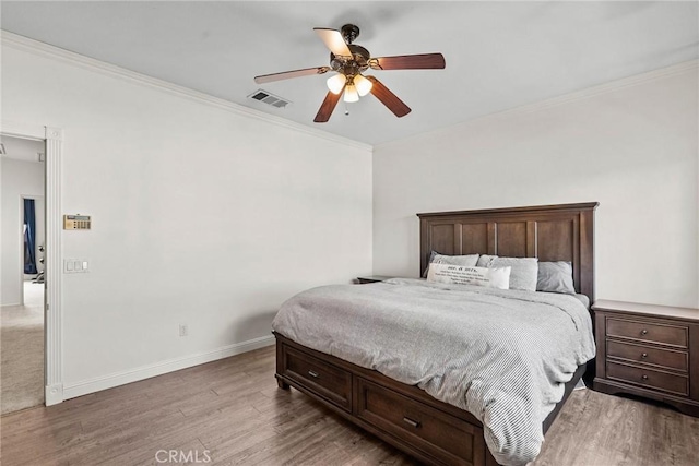 bedroom with visible vents, ornamental molding, a ceiling fan, wood finished floors, and baseboards