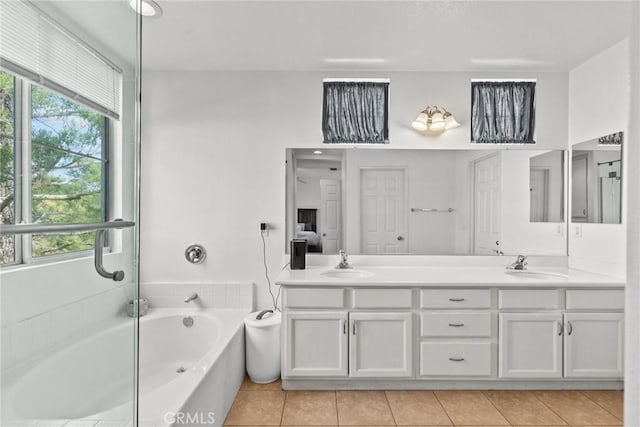 ensuite bathroom featuring double vanity, a sink, and a bath