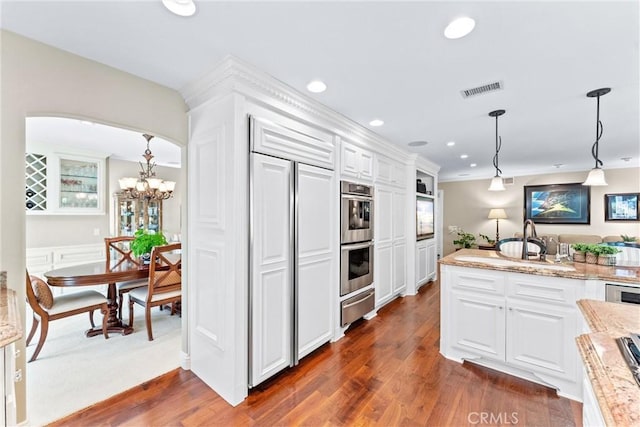 kitchen with light stone counters, pendant lighting, white cabinets, and a warming drawer