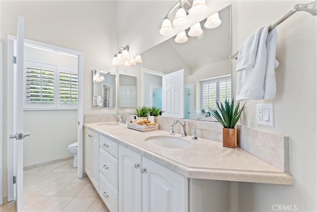 bathroom with tile patterned floors, a sink, toilet, and double vanity