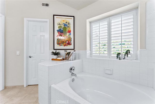 bathroom featuring lofted ceiling, tile patterned flooring, visible vents, and a bath