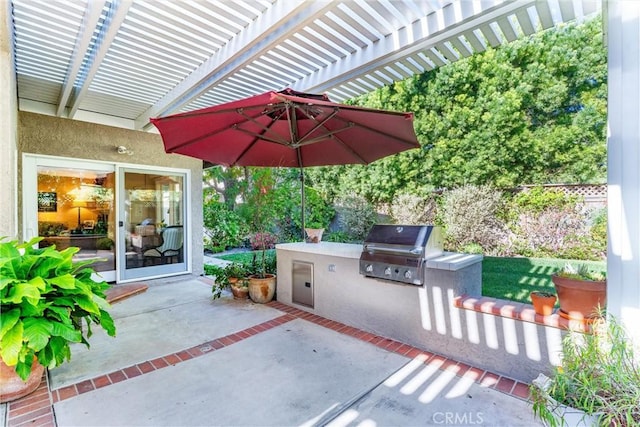 view of patio with area for grilling, fence, an outdoor kitchen, and a pergola