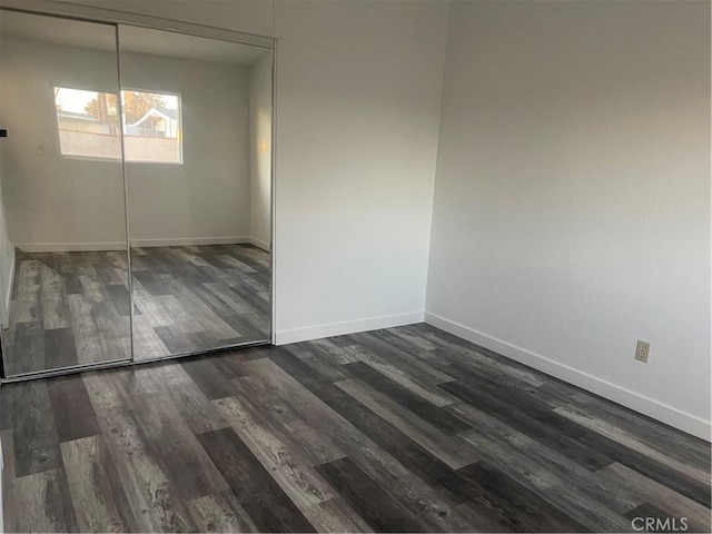 unfurnished bedroom with dark hardwood / wood-style flooring and a closet