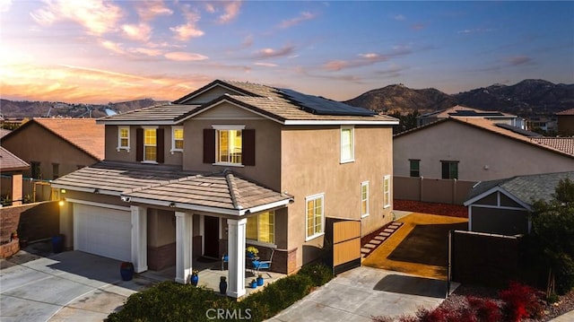 view of property featuring a garage, a mountain view, and solar panels