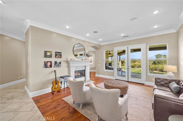 living room featuring light hardwood / wood-style flooring, crown molding, and french doors