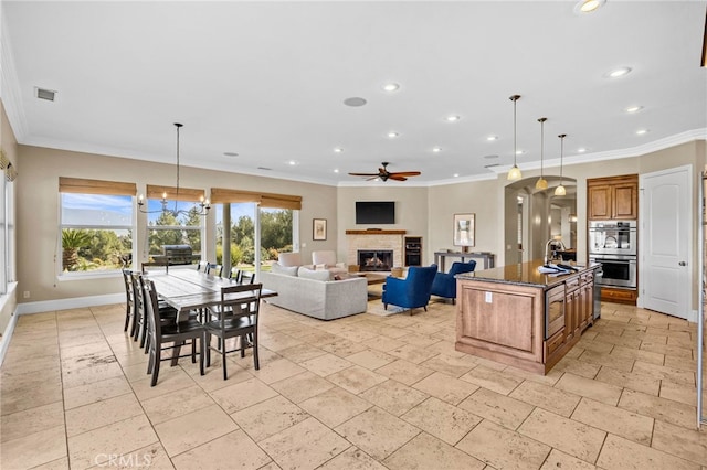 kitchen featuring dark stone countertops, sink, a center island, stainless steel double oven, and hanging light fixtures