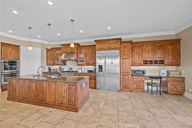 kitchen featuring dark stone countertops, a kitchen island with sink, stainless steel appliances, and decorative light fixtures