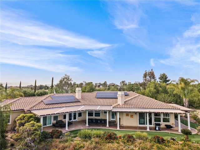 rear view of house featuring a patio and solar panels