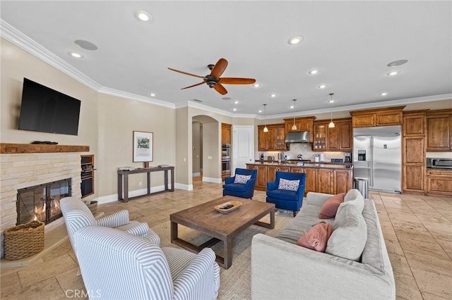 living room featuring a fireplace, ceiling fan, and crown molding