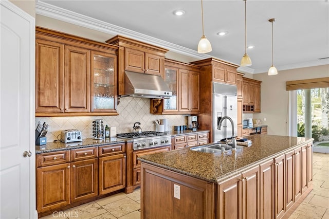 kitchen featuring a center island with sink, sink, ornamental molding, dark stone counters, and pendant lighting