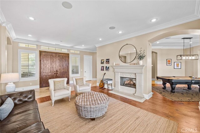 living room with light wood-type flooring, a premium fireplace, billiards, and crown molding