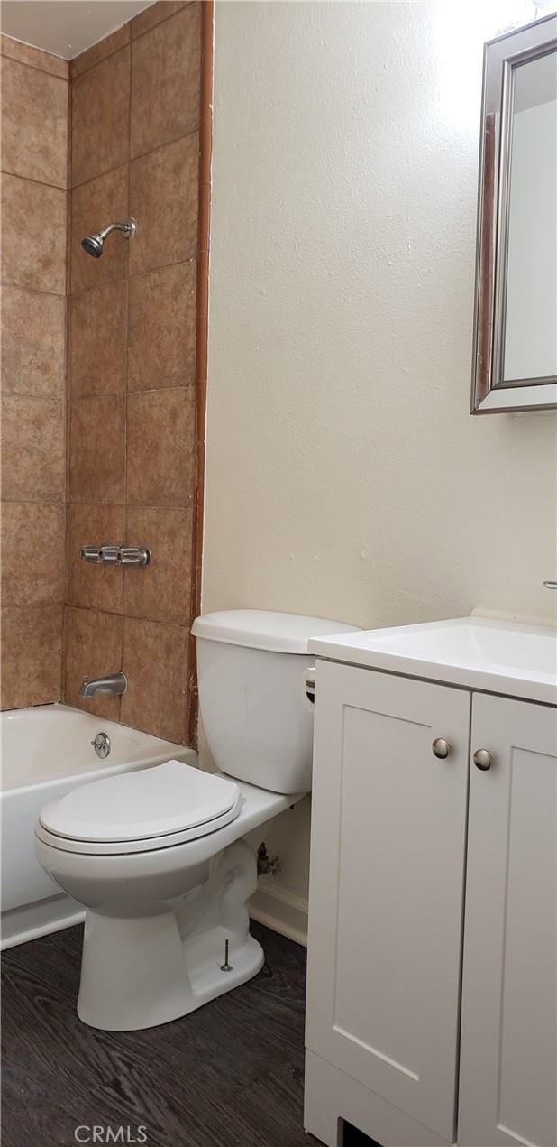 full bathroom with tiled shower / bath combo, vanity, hardwood / wood-style floors, and toilet