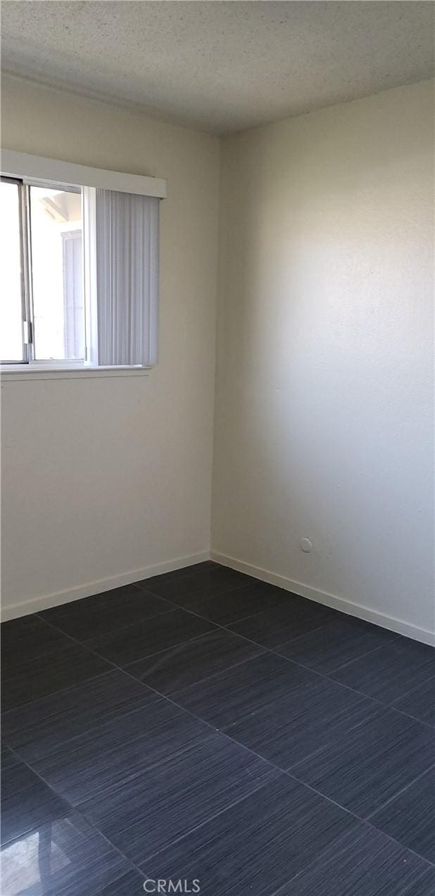 tiled spare room featuring a textured ceiling