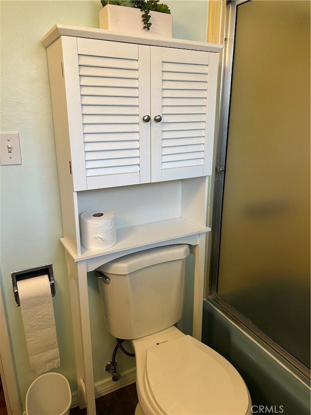 bathroom with enclosed tub / shower combo, toilet, and hardwood / wood-style floors