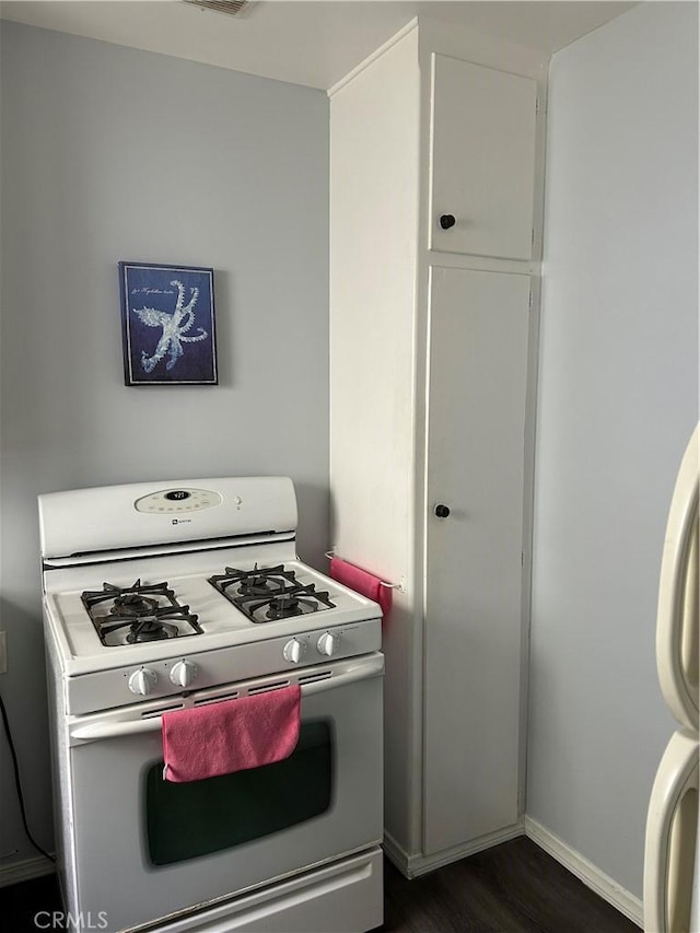 kitchen featuring white gas range, dark wood-type flooring, and white cabinets