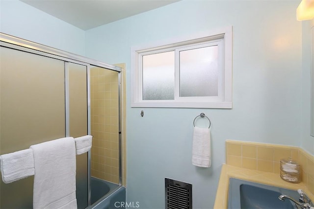 bathroom featuring combined bath / shower with glass door and sink