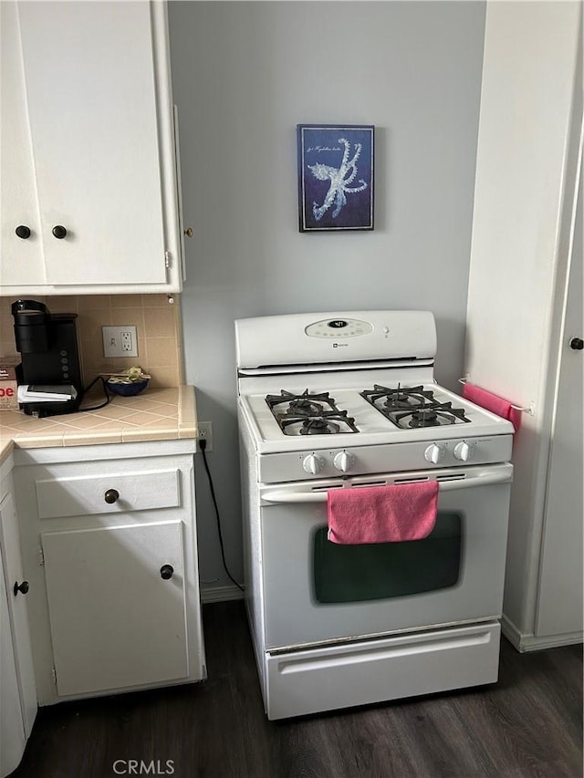 kitchen with tile countertops, dark hardwood / wood-style flooring, white cabinets, white gas range oven, and backsplash