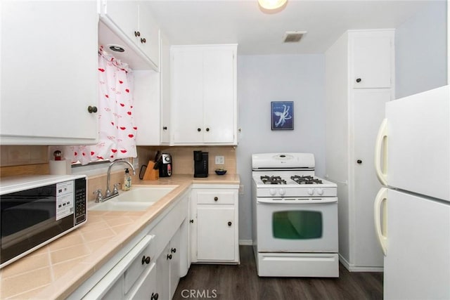 kitchen featuring visible vents, dark wood-type flooring, a sink, white appliances, and white cabinets