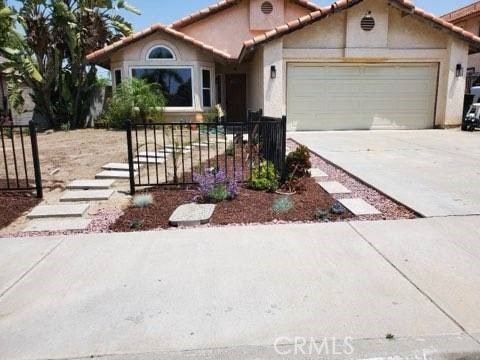 view of front of home with a garage, a tile roof, driveway, and stucco siding