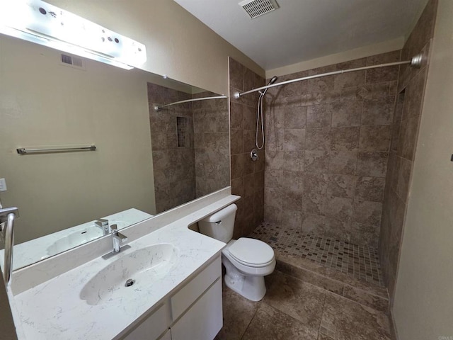 full bath featuring toilet, visible vents, tiled shower, and vanity