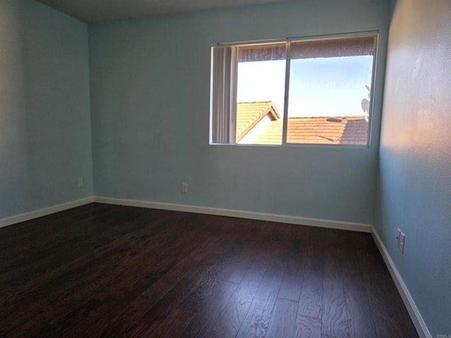 unfurnished room with dark wood-style floors and baseboards