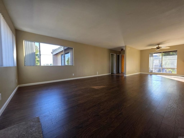 unfurnished room with a ceiling fan, dark wood-style flooring, and baseboards